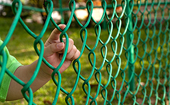 A child's hand holding onto a Chain Link Fence in Bloomington IL