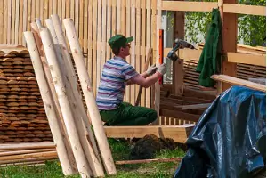 A fence installer is seen working on a new fence. How Do I Maintain My Wood Fence? Call Hohulin Fence!