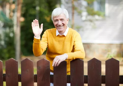 A friendly neighbor leaning over the fence and saying hello, adhering to proper fencing etiquette